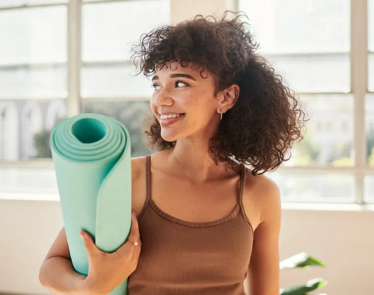Woman holding yoga mat smiling