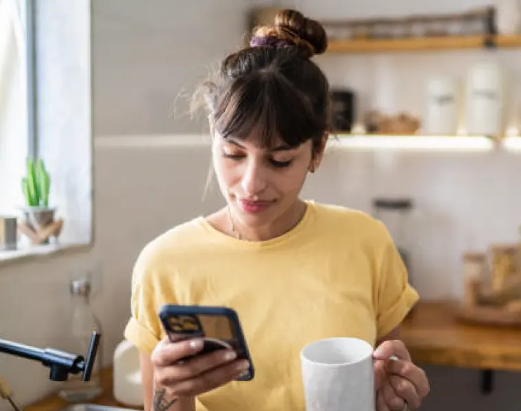Woman looking at phone with coffee