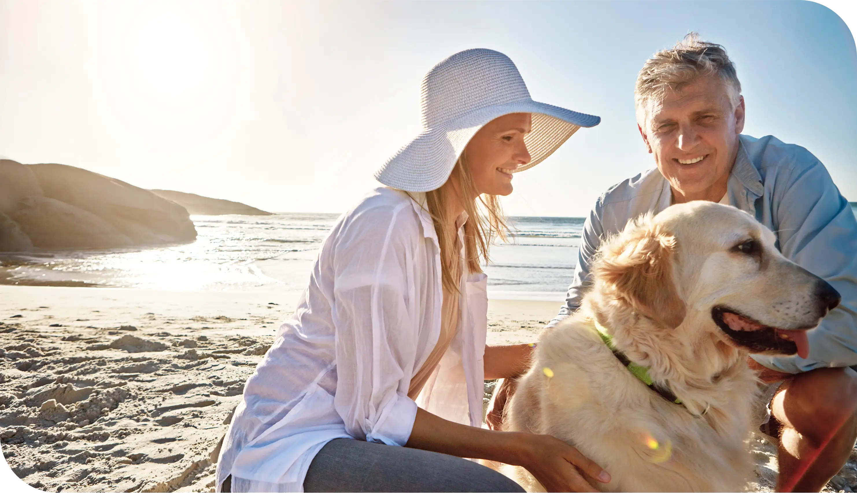 Senior couple smiling on the beach with their golden retriever, symbolizing retirement lifestyle and healthcare security through Medicare Supplement coverage.