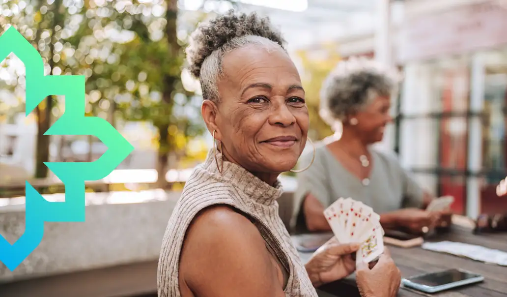 Older woman smiling while playing cards with friends