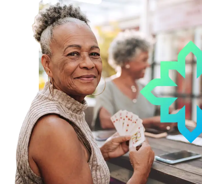 Older woman smiling while playing cards with friends
